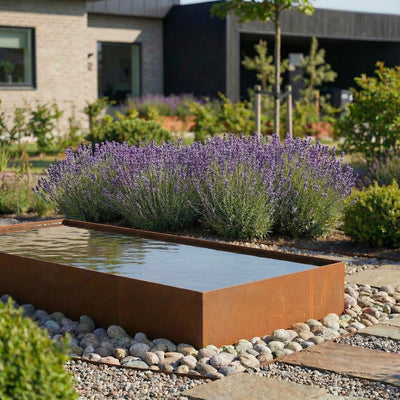 Eine lange Wasserbecken aus cortenstahl in einem schönen garten.  
